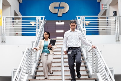 Empleados de Colgate-Palmolive bajando un tramo de escaleras con el logotipo de Colgate-Palmolive detrás de ellos sobre una pared azul.